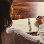 Escritor mirando una hoja en blanco mientras intenta superar el bloqueo creativo